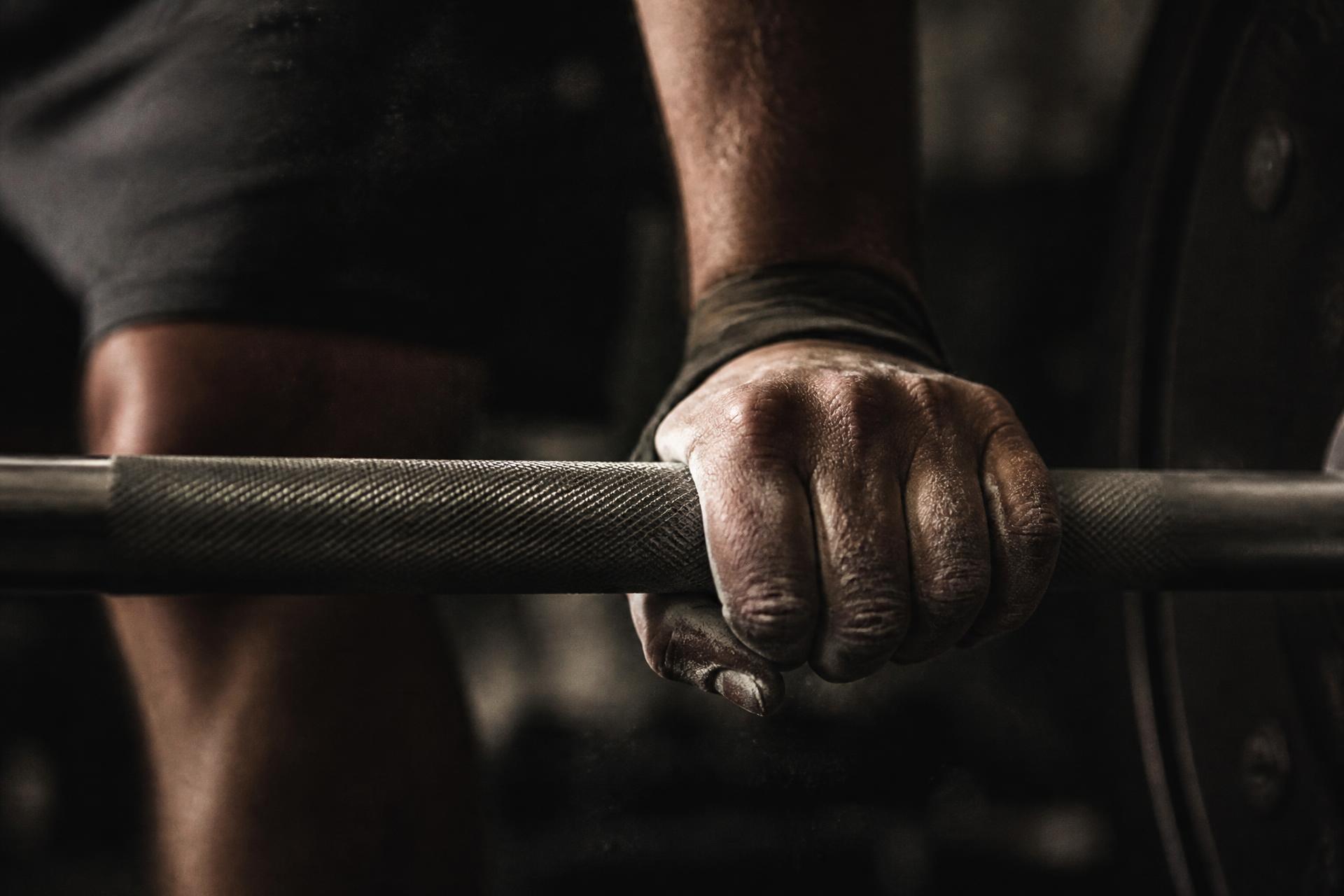 Chalk-covered hands gripping a barbell